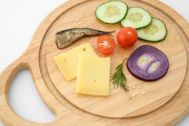 Peynir ve sebzeler doğrama tahtasında. Soğan, salatalık, vişneli domates ve baharat karışımı..