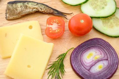 Peynir ve sebzeler doğrama tahtasında. Soğan, salatalık, vişneli domates ve baharat karışımı..