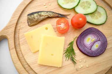 Peynir ve sebzeler doğrama tahtasında. Soğan, salatalık, vişneli domates ve baharat karışımı..
