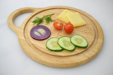 Peynir ve sebzeler doğrama tahtasında. Soğan, salatalık ve kiraz domatesleri..