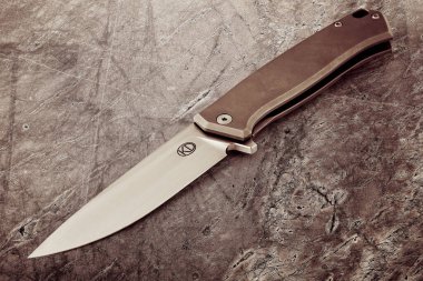 Taş bir masa yüzeyinde keskin çelik bir katlama bıçağı. Genel tasarım, turizm, avcılık, erkeğin tutku konsepti.