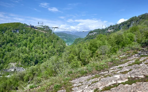 Scenic view of rocky slopes with a sky bridge and cable car for bungee jumping in the background. Akhshtyrskiy canyon Adler microdistrict, Russia. Concept of extreme sports, activities, challenges.
