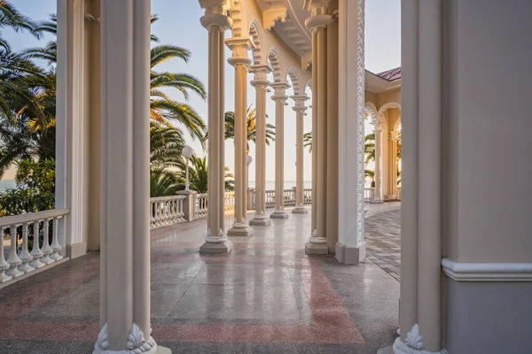 Gün batımında Ghagra Colonnade 'nin sütunları ve mermer zemini. Tarihi mimari yapı, Karadeniz 'in ve kıyılarının manzarasını palmiyelerle açıyor. Manzaralar, seyahat, turizm.