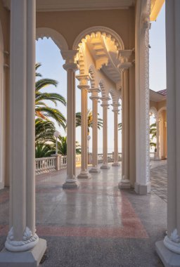 Gün batımında Ghagra Colonnade 'nin sütunları ve mermer zemini. Tarihi mimari yapı, Karadeniz 'in ve kıyılarının manzarasını palmiyelerle açıyor. Manzaralar, seyahat, turizm.