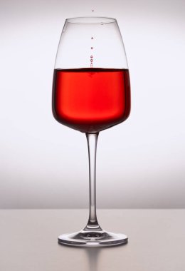 Arka planda donmuş damlacıklarla kırmızı şarap kristal kadehinin yakın çekimi. Dalgalı bir yüzey. Restoran bardakları, içecekler, sofra kurma, tutku, aşk, parti, su sıçramaları..