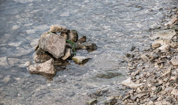 A pile of stones at the riverside. Transparent water with reflections and rocky banks. Rural landscapes by the water.