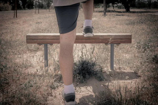 a man doing exercises in a park on a sunny day on shorts viewing his feet