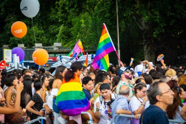 Eğlenen ve gökkuşağı bayrakları dalgalanan insanlar yaz gay onur yürüyüşünde
