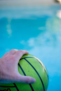 Suyun içinde lastik topu tutan bir elin dikey fotoğrafı.