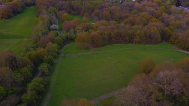 Pan inverso aéreo sobre parques verdes rodeados de árboles primaverales — Vídeo de stock