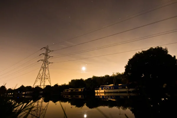 Вечірня сцена лондонського каналу з місяцем, електричними лініями і човном. — стокове фото