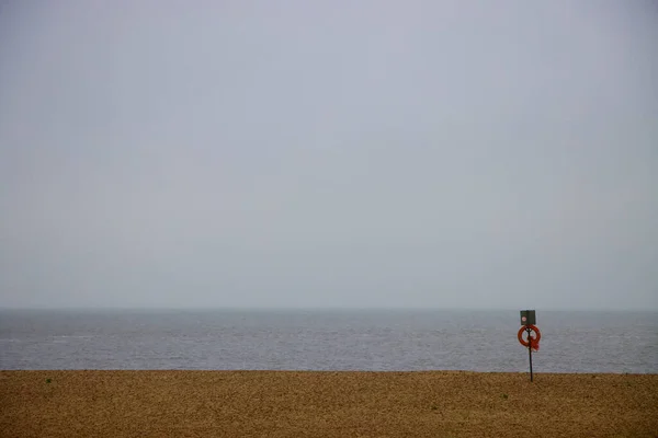 Scéna na pláži s kruhem záchranné bóje a liniemi písku, moře a mraků — Stock fotografie
