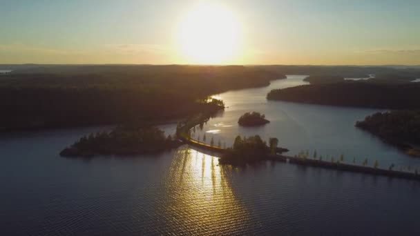 Vista aérea do lago pôr-do-sol. Sol refletindo sobre a água. Estrada estreita atravessando o lago — Vídeo de Stock