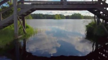 Küçük ahşap bir köprünün altında uçmak ve güzel göl manzarasını gözler önüne sermek. Gölde kayık. 