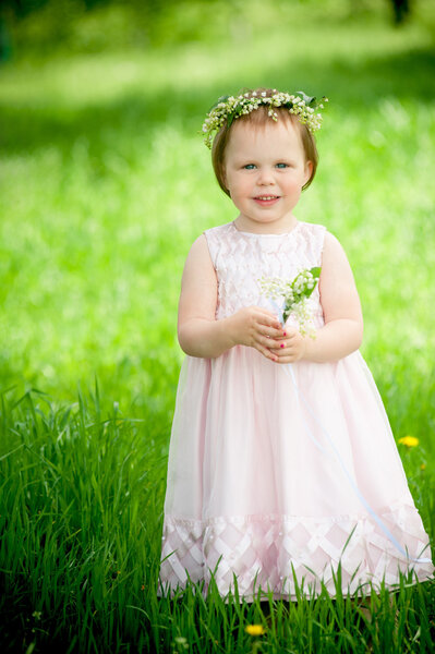 Sweet baby girl in wreath of flowers smiling outdoors