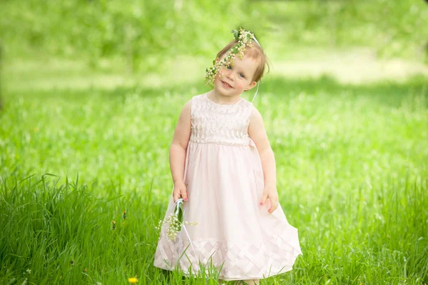 Sweet baby girl in wreath of flowers smiling outdoors — Stock Photo, Image