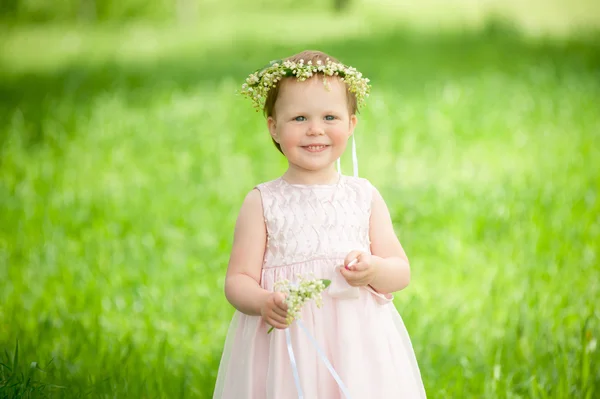 Dulce niña en corona de flores sonriendo al aire libre — Foto de Stock