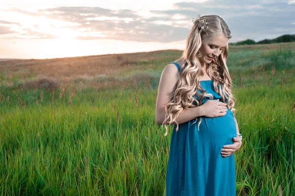 Beautiful tender pregnant woman standing on green grass — Stock Photo, Image