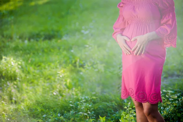 Hermosa mujer embarazada tierna de pie en el prado verde — Foto de Stock