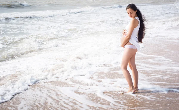 Piękna kobieta w ciąży przetargu stać na brzegu morza — Zdjęcie stockowe