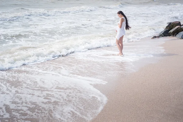 Красивая нежная беременная женщина стоит на берегу моря — стоковое фото