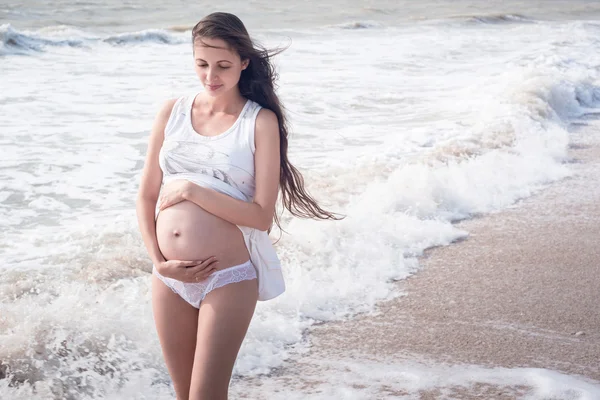 Beautiful tender pregnant woman stand on the sea shore Royalty Free Stock Images