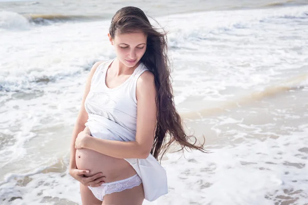 Beautiful tender pregnant woman stand on the sea shore Stock Photo