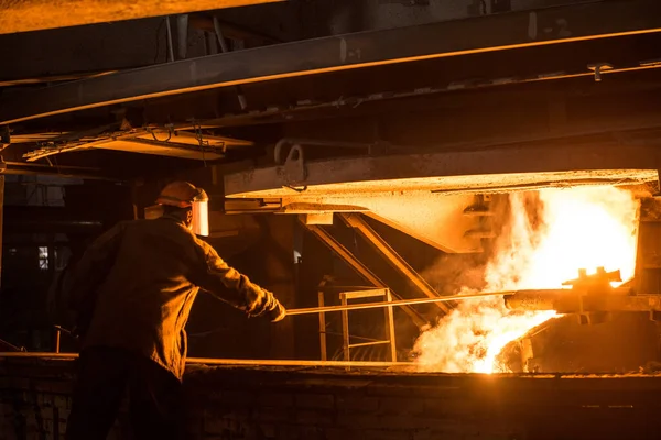 Steelworker when pouring liquid metal from arc furnace