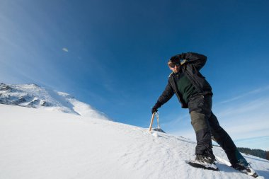 Karlı dağlarda elinde baltayla tırmanıyor.