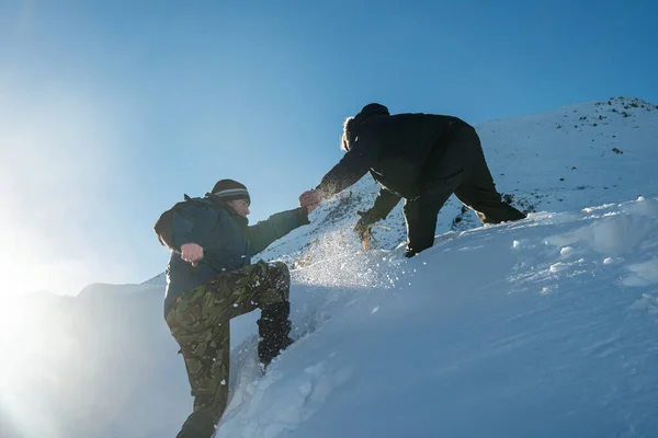 登山者在雪山的斜坡上帮助另一位登山者 — 图库照片