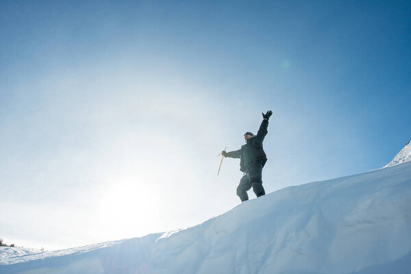 Happy climber with an ice ax in the snowy mountains