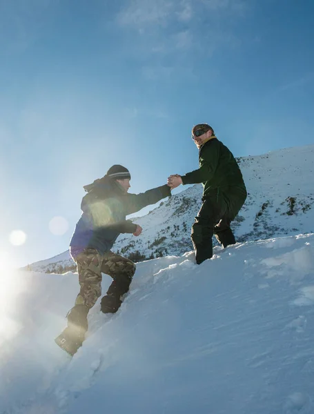 登山者在雪山的斜坡上帮助另一位登山者 — 图库照片