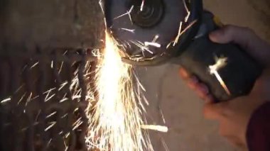 Öğütücü kullanan işçilere yakın çekim bir atölyede metal kesiyor.