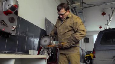 Öğütücü kullanan işçi bir atölyede metal kesiyor.
