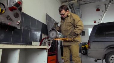 Öğütücü kullanan işçi bir atölyede metal kesiyor.
