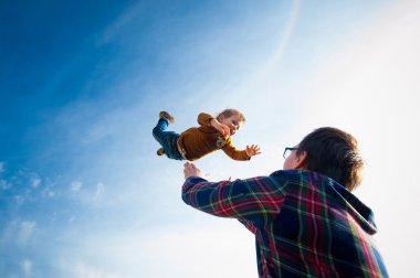 adam çocuğu gökyüzüne atar.
