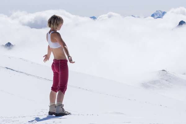 Girl blonde in the snowy mountains high above the clouds
