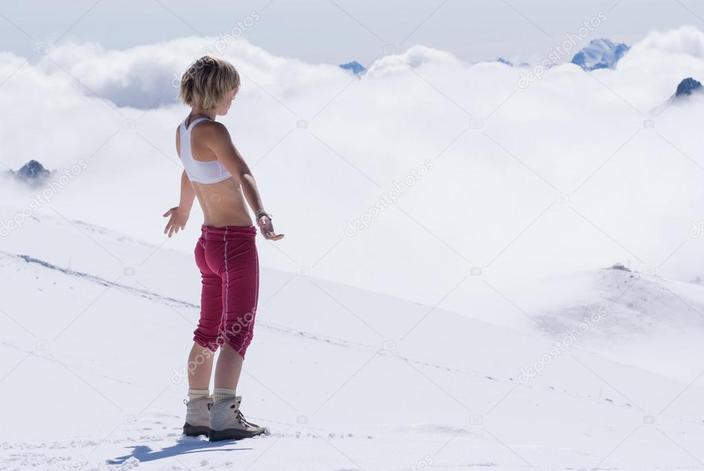 Girl blonde in the snowy mountains high above the clouds