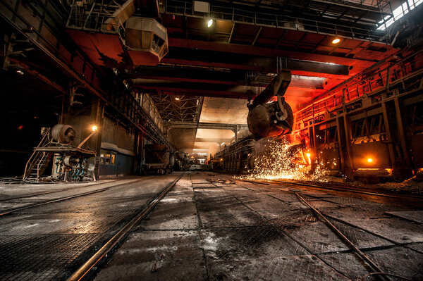 из ковша льется раскаленная сталь
