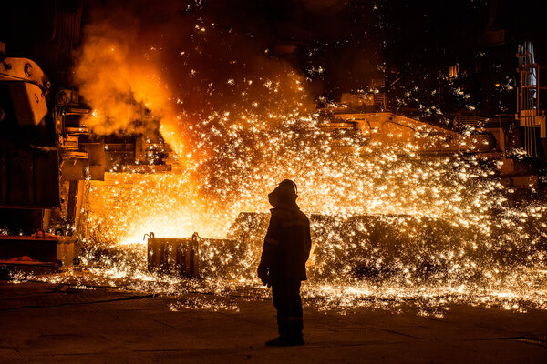Steelworker near a blast furnace with sparks