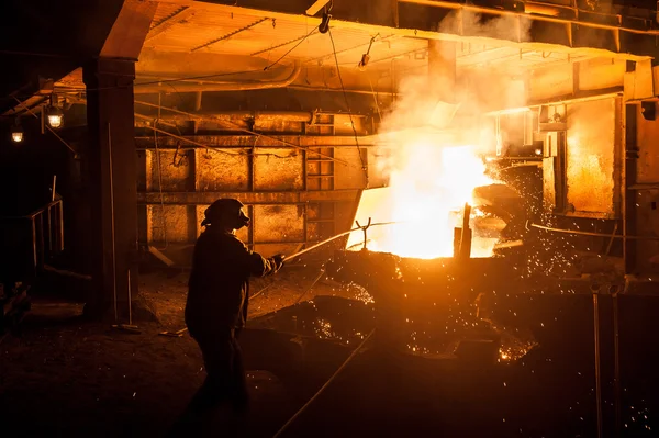 Trabajador siderúrgico al verter escoria líquida de titanio del horno de arco — Foto de Stock