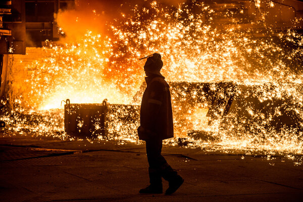 Steelworker near a blast furnace with sparks