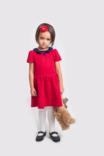 Malheureux belle petite fille dans une robe rouge avec un ours jouet — Photo