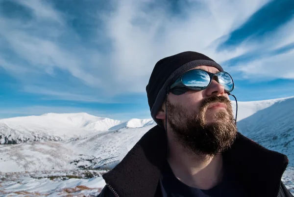 Портрет человека в очках и с бородой в снежных горах — стоковое фото