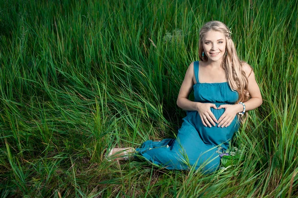 Hermosa mujer embarazada tierna sentada sobre hierba verde — Foto de Stock