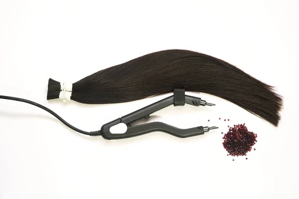 Eine Haarsträhne zur Verlängerung mit einer Vorrichtung zur Verkapselung und Keratin in Granulat auf weißem Hintergrund — Stockfoto