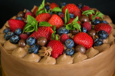 Çilek, ahududu ve yaban mersiniyle süslenmiş çikolatalı pasta..