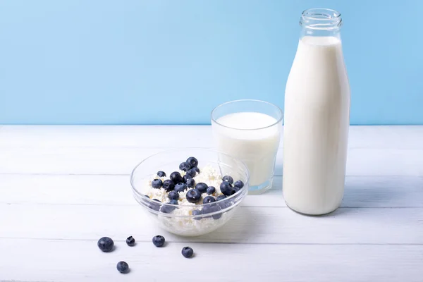 Fresh blueberries and milk products on white wooden table on a blue background. with central focus and shallow depth of field — Stock Photo, Image