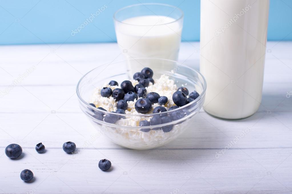 Close view of fresh dairy products with blueberry on wooden table on natural background. Shallow depth of field.