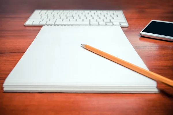 Pencil lying on a notepad with keyboard and mobile phone on a background. Shallow depth of field. — Stock Photo, Image